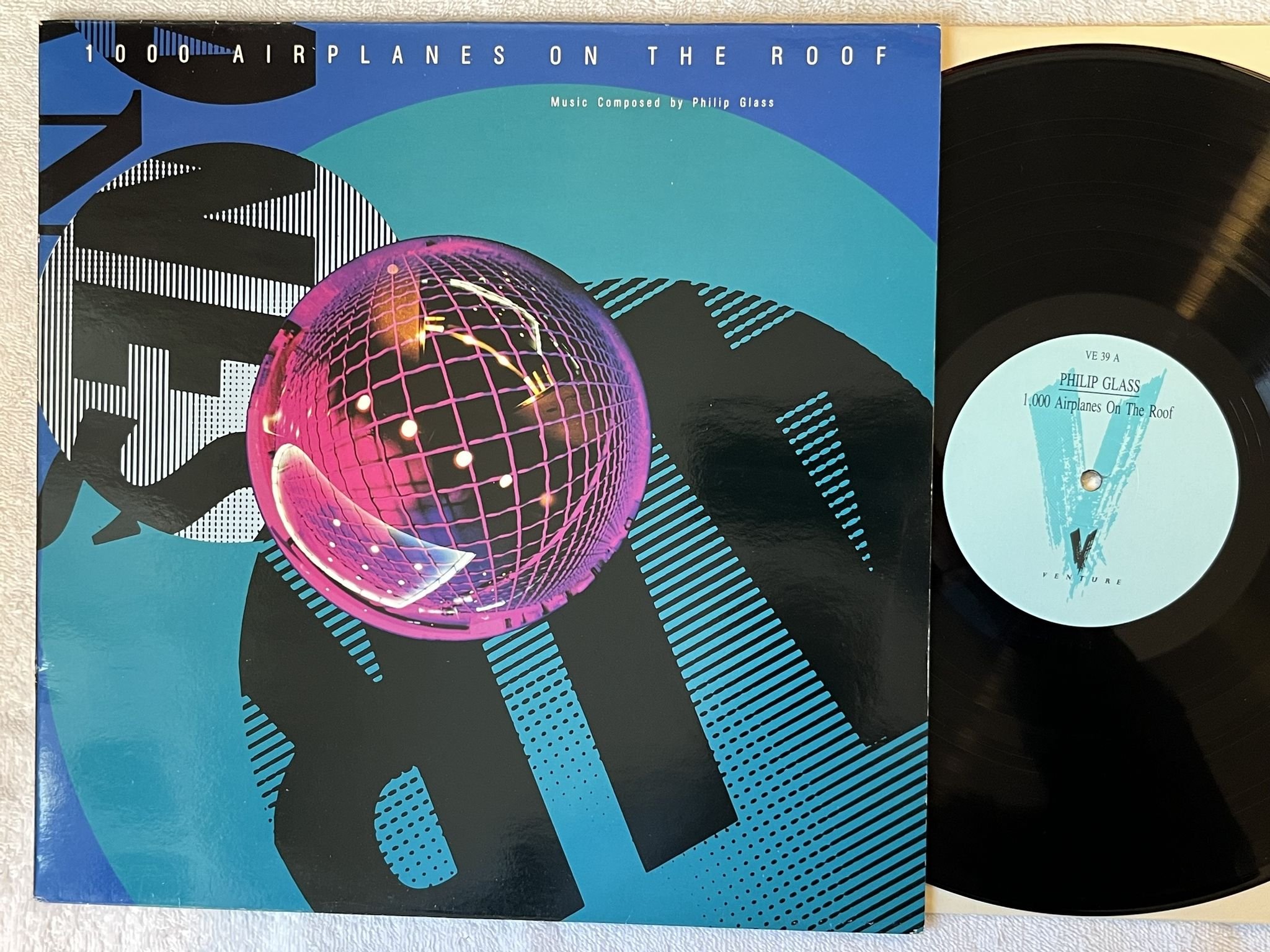 Omslagsbild för skivan PHILIP GLASS 1000 Airplanes On The Roof LP -89 UK venture VE-39