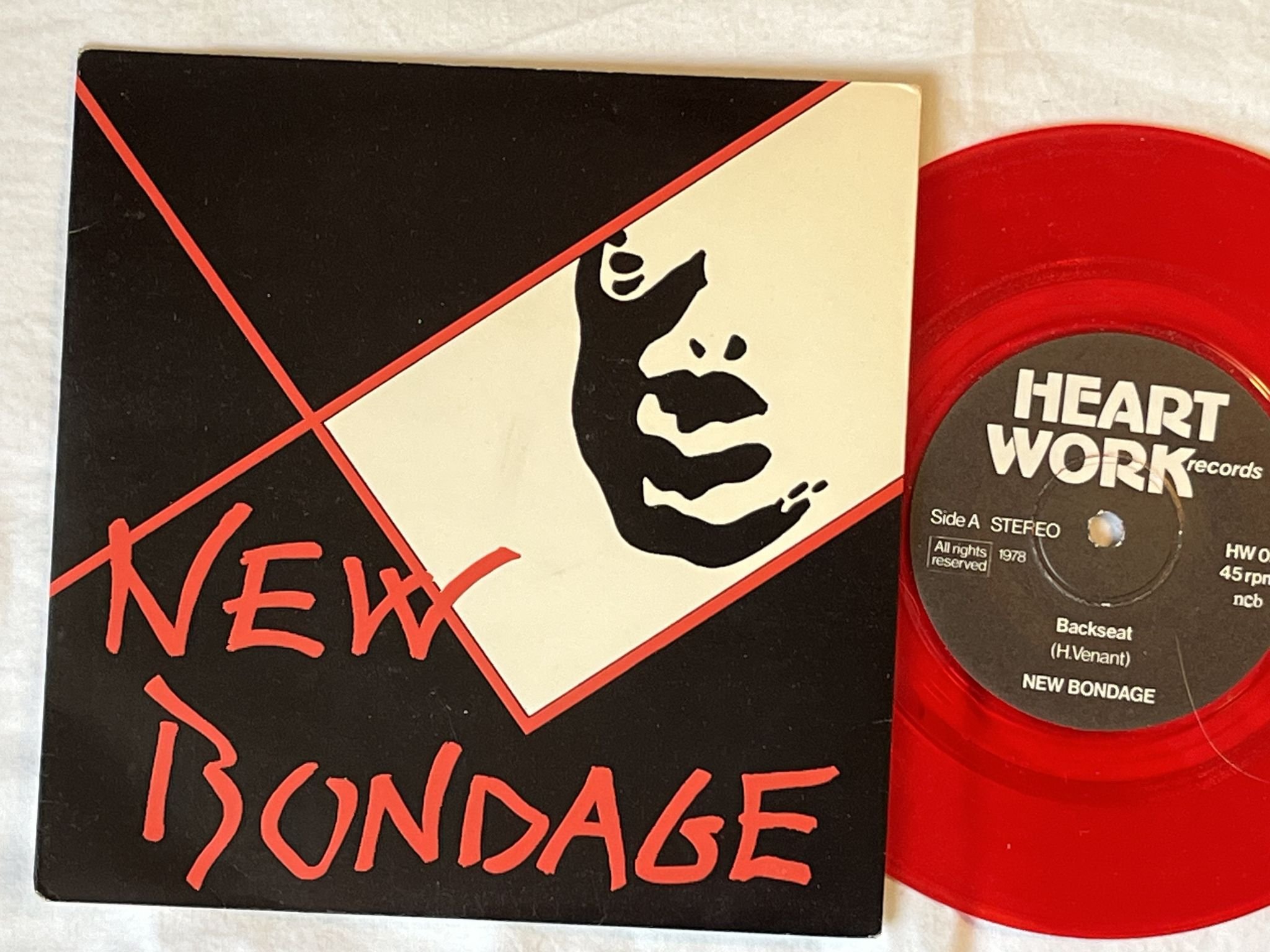 Omslagsbild för skivan NEW BONDAGE back seat 7" -78 Swe HEARTWORK HW 02 *** RED VINYL ***