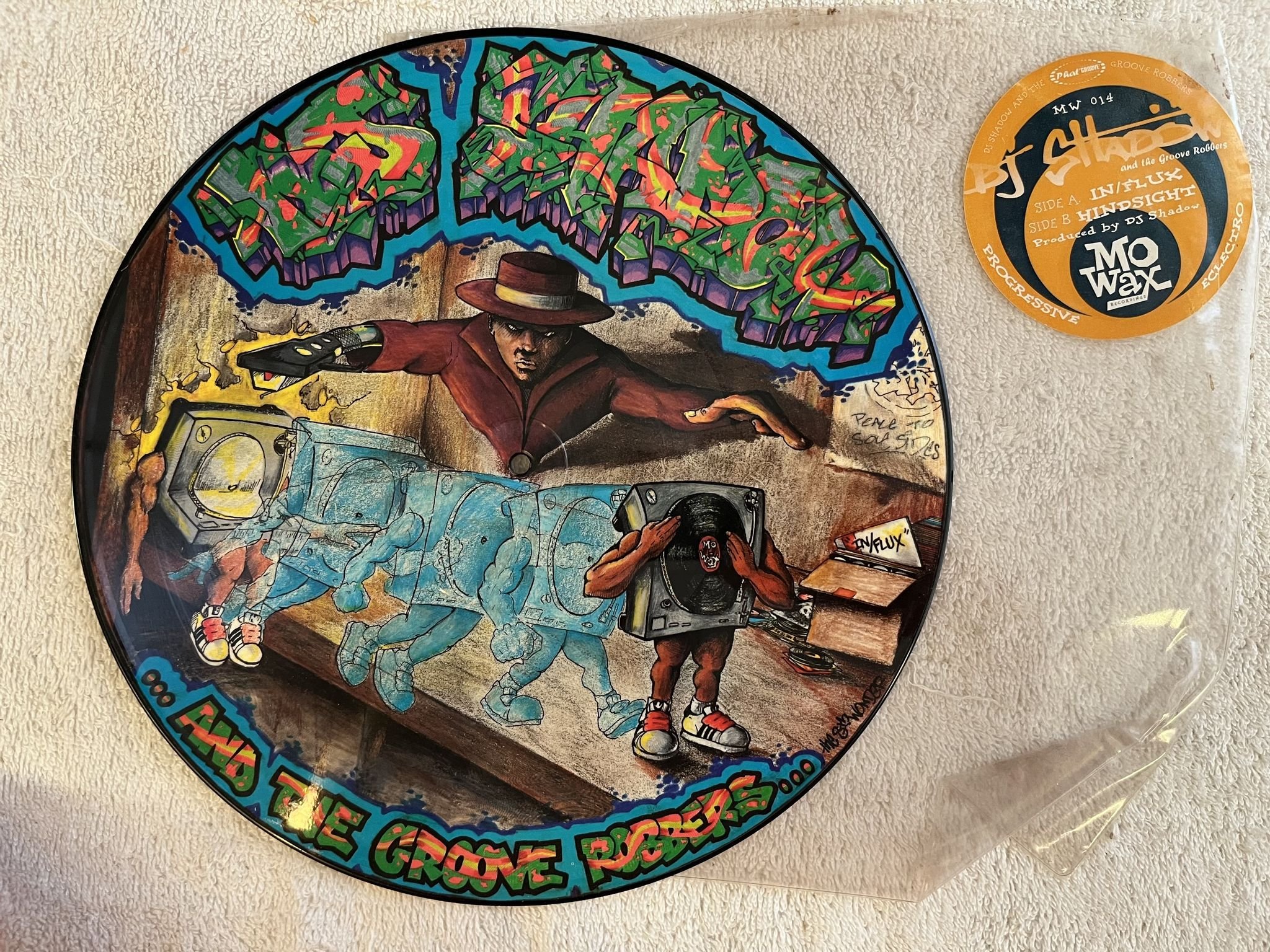 Omslagsbild för skivan DJ Shadow .. And The Groove Robbers... – In/Flux 12" UK -93 MO WAX MW 014